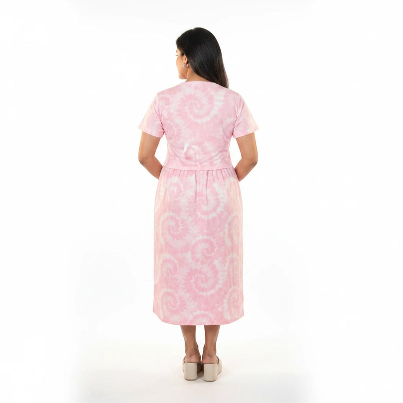 Back view of a woman wearing a CozyFab pink tie-dye midi dress with short sleeves and a relaxed fit.